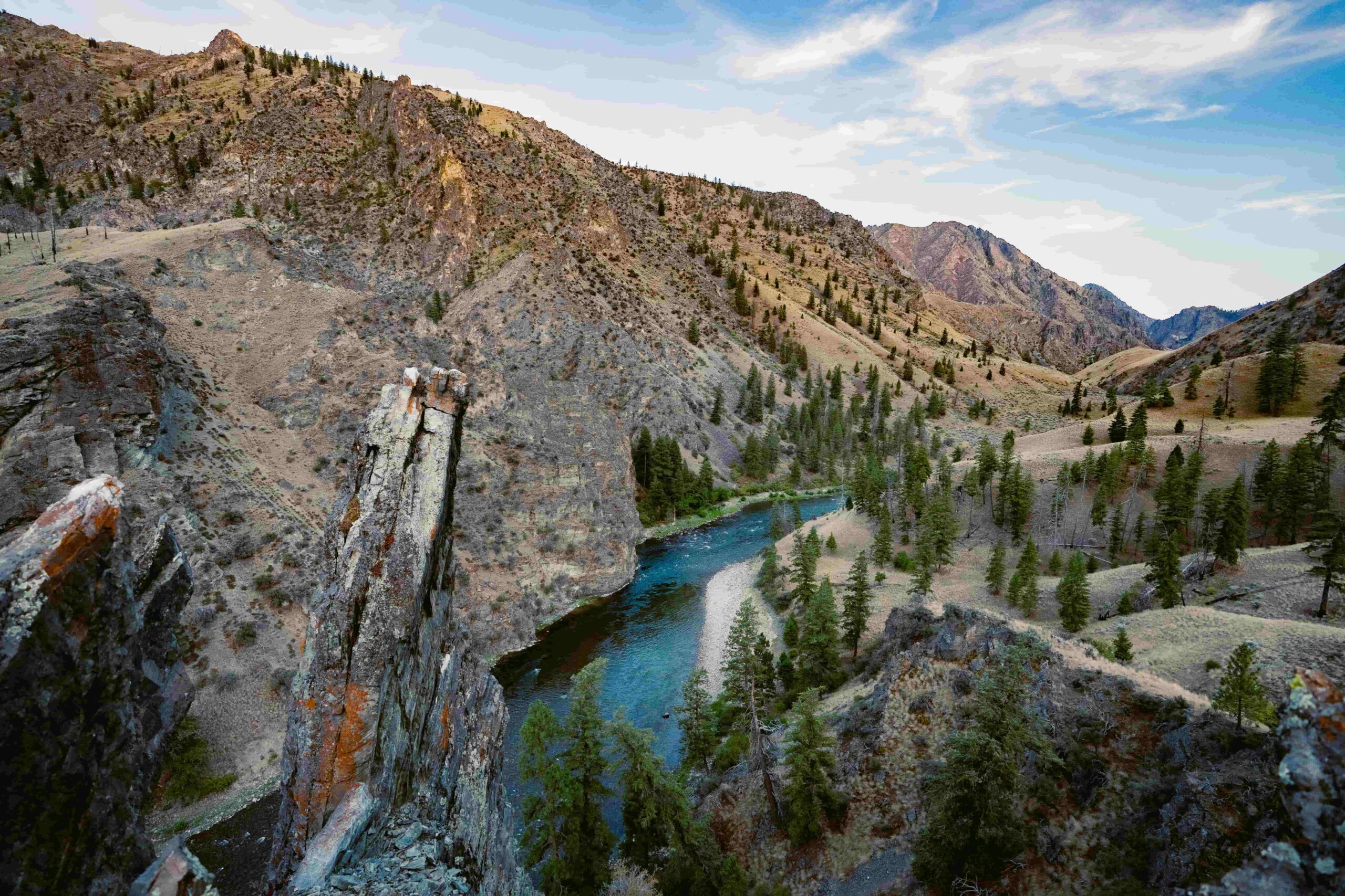A view of the river from high above, with jagged cliffs and mountains surrounding. 