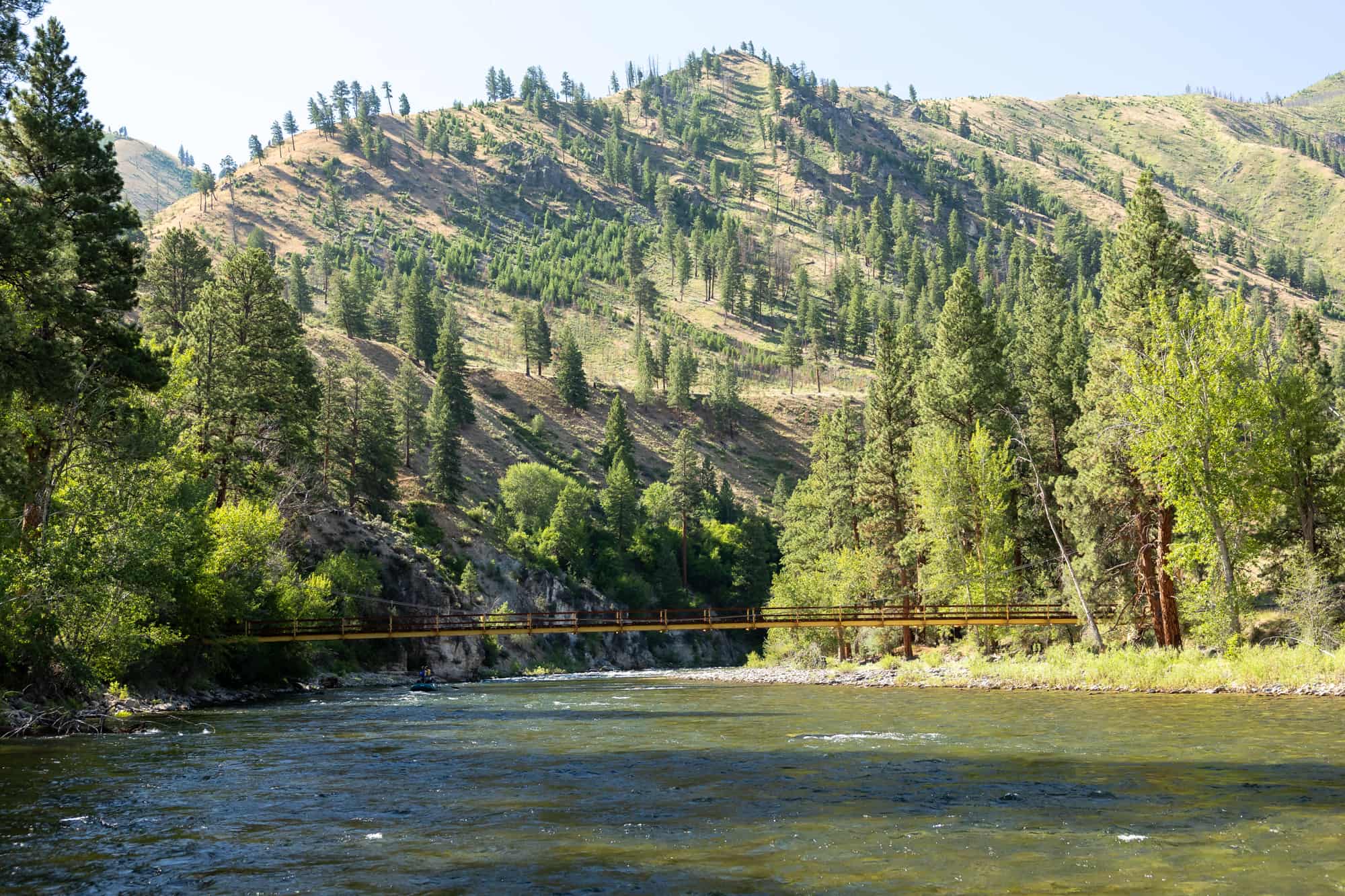 The bridge over the Middle Fork of the Salmon River, built with cables and with mountains in the background. 